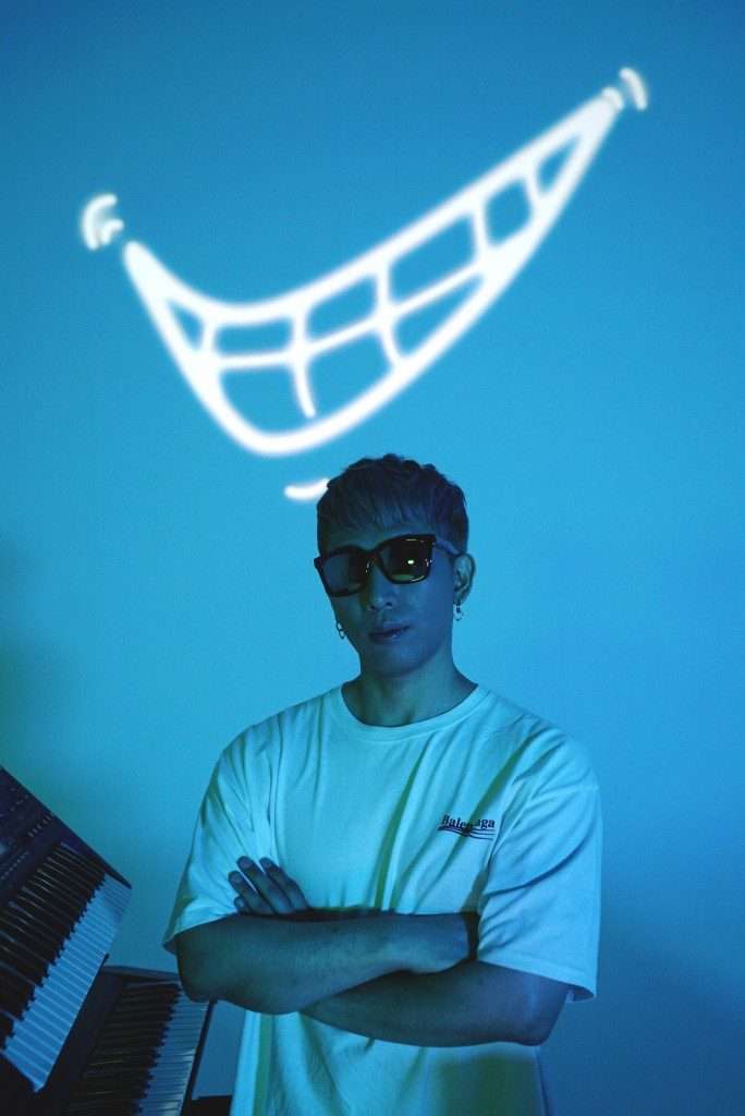 RTMKNG South Korean electronic music producer and DJ posing in a creative studio with blue lighting