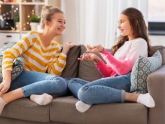 2 girls talking on a brown couch