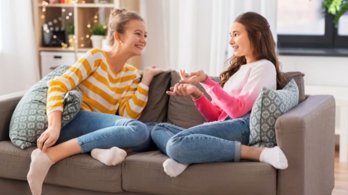 2 girls talking on a brown couch