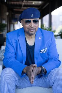 elegant middle black male in a blue suit and nay blue shirt wearing Rayban sunglasses