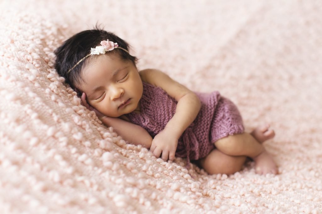 baby girl sleeping on pink bed
