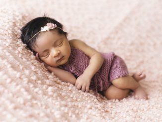 baby girl sleeping on pink bed