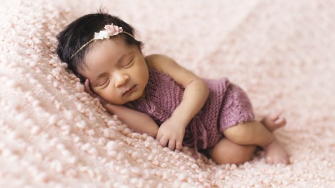 baby girl sleeping on pink bed