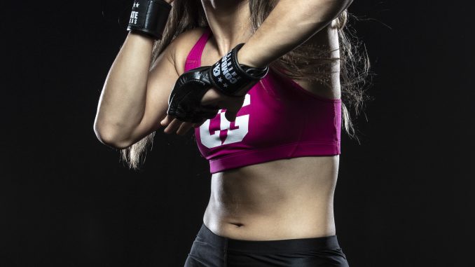 MMA fighter woman wearing a pink top and black boxing gloves