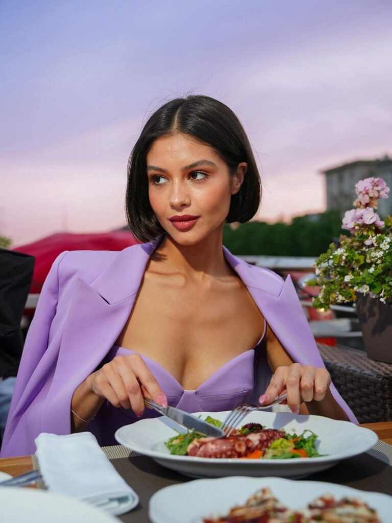 Stylish woman eating a healthy salad outdoors – glow-up meal inspiration from Pump It Up Magazine's Revenge Body 2025 feature