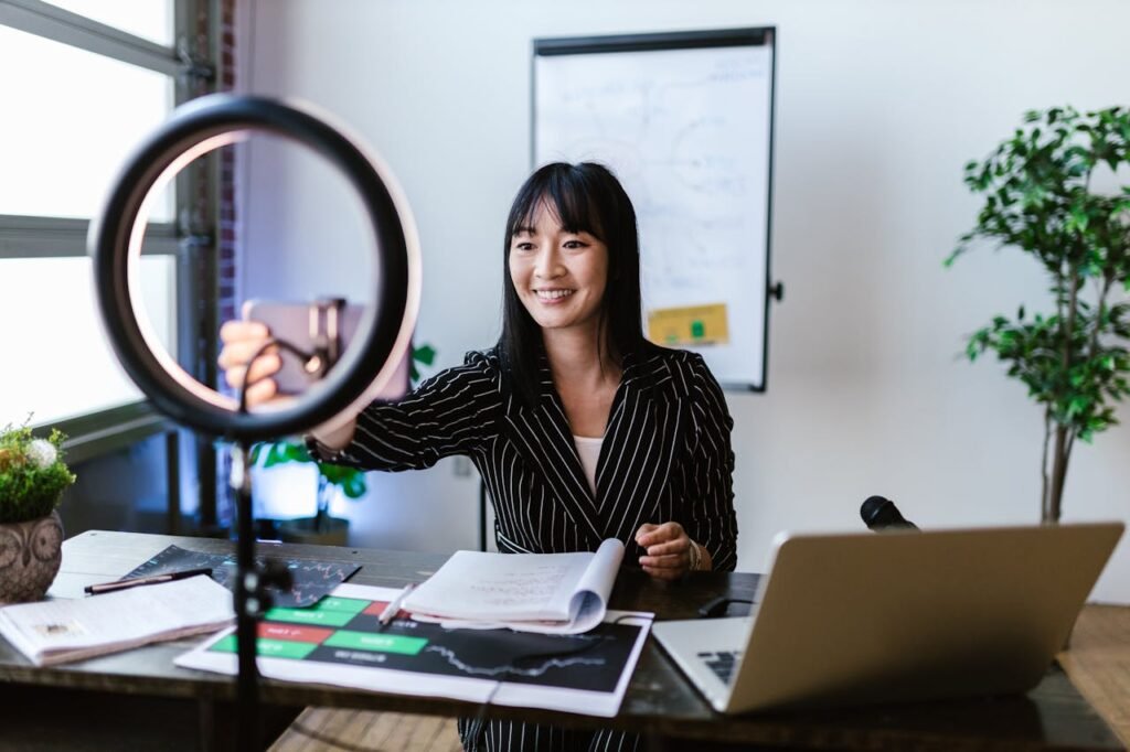 Businesswoman recording a video blog in an office using a smartphone and ring light