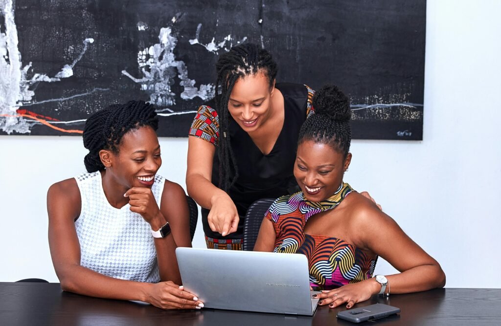 Three businesswomen collaborating with a laptop, symbolizing teamwork, leadership, and business skills for success.