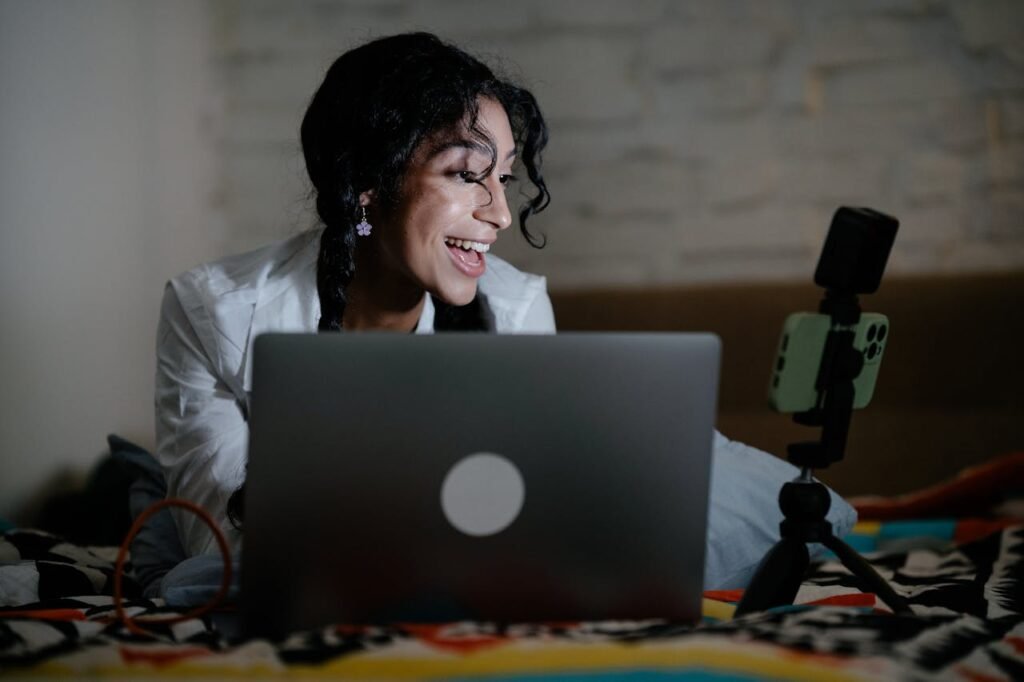 Woman recording a remote podcast with a smartphone and laptop at home