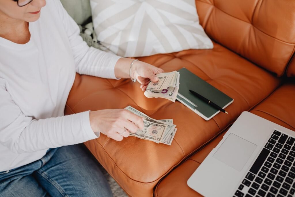 woman-sitting-and-counting-money-in-front-of-a-laptop