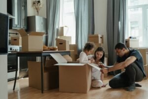 A young family packing moving boxes together in their living room, preparing for a house relocation