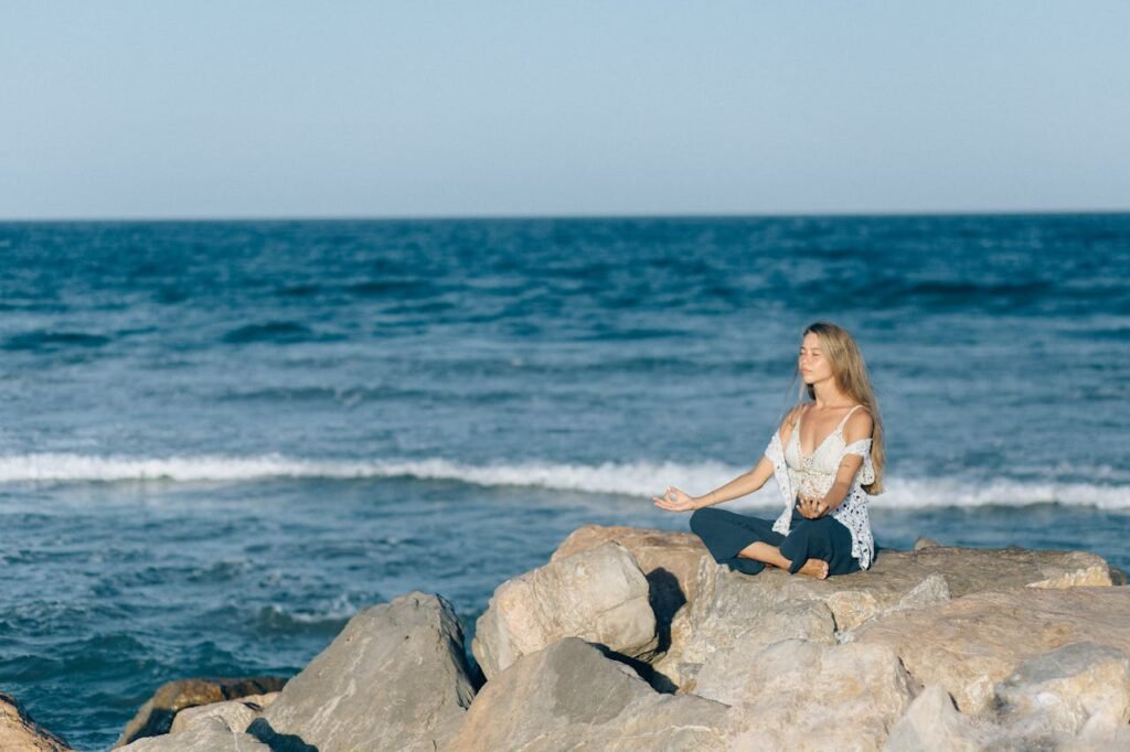 Woman meditating by the ocean during one of the Mental Health Retreats in California