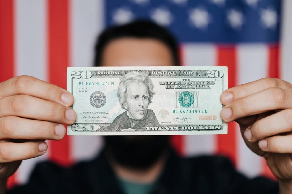 Man holding a $20 bill in front of an American flag – symbolizing money tips for immigrants in America