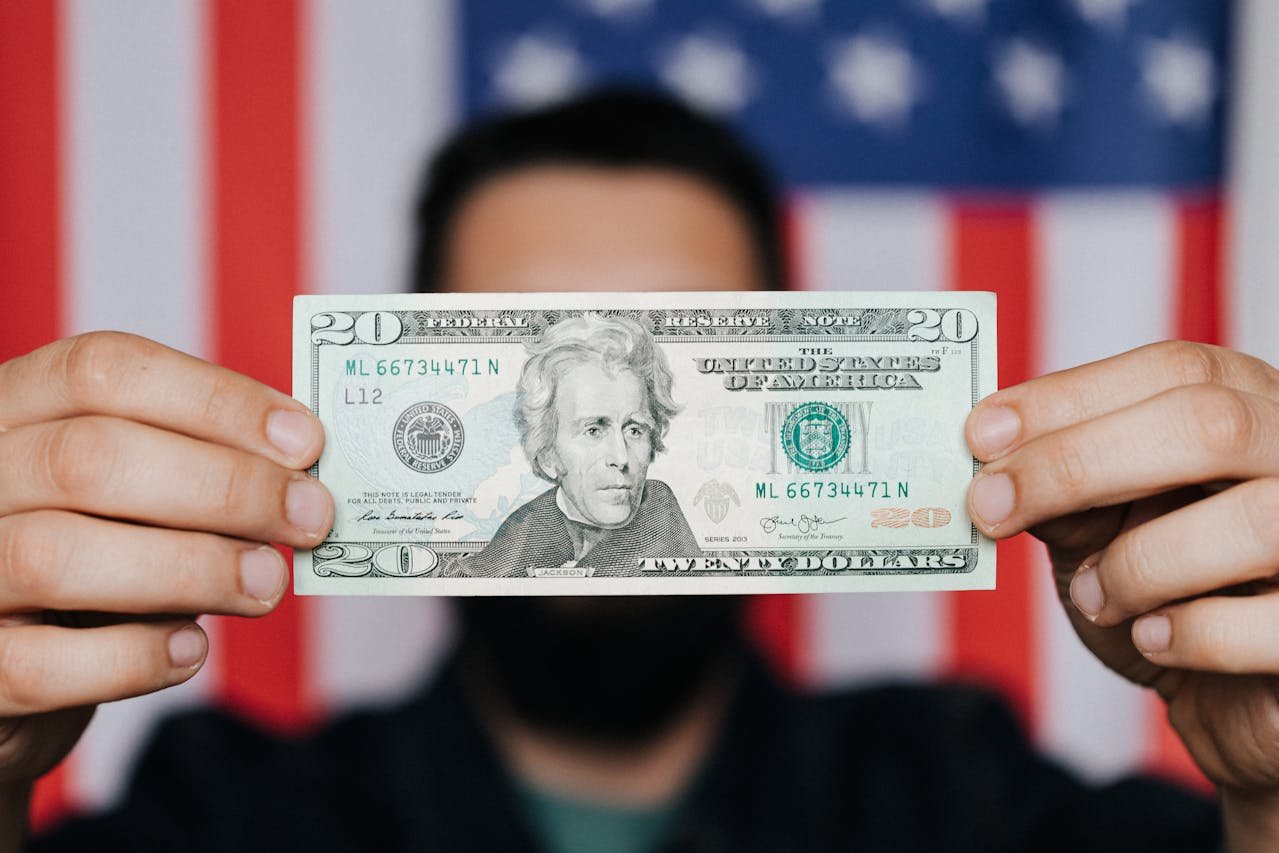 Man holding a $20 bill in front of an American flag – symbolizing money tips for immigrants in America