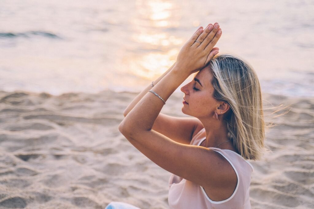 Woman meditating by the ocean during one of the Mental Health Retreats in California