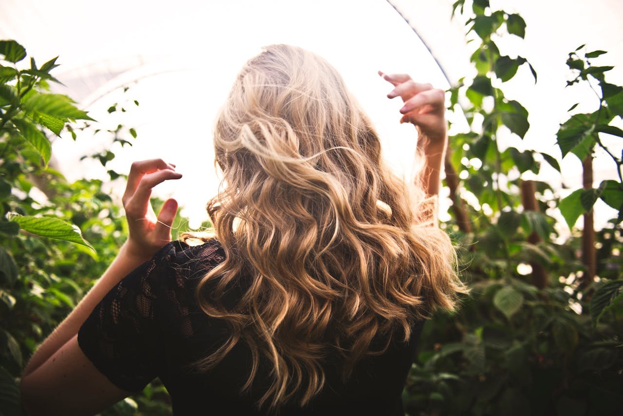blonde-haired-woman-standing-between-green-plants
