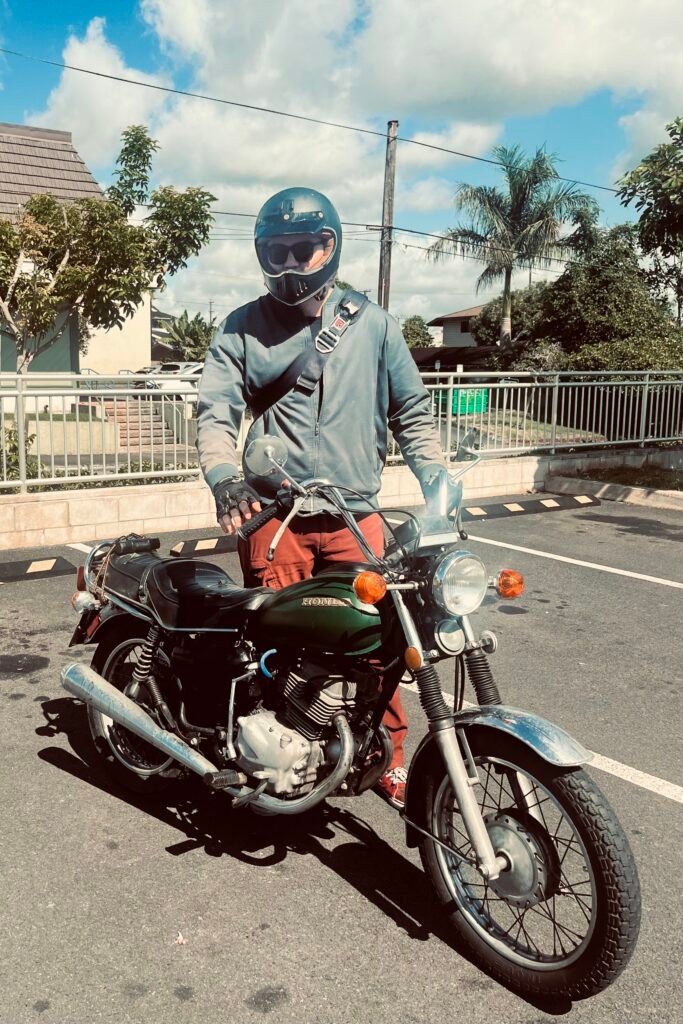 Harrison Monroe gears up for the road, blending indie grit with timeless cool on his classic Honda bike.