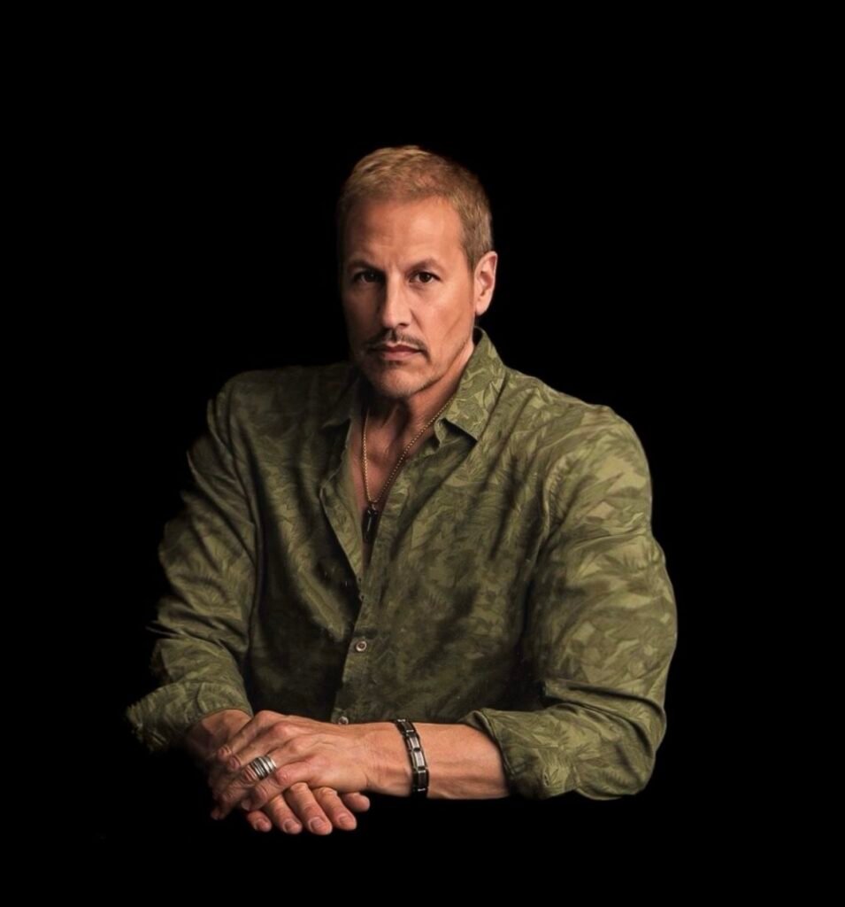Michael Cates wearing a green shirt, seated against a black background