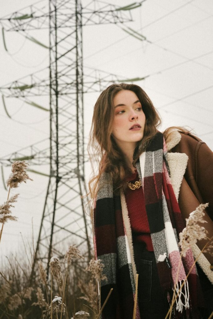 Olive utility-style jacket layered over knit with scarf, outdoors in natural light.