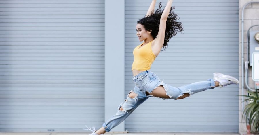 Beautiful woman leaping outdoors in casual fitness style, showing fun workout without the gym – Pump It Up Magazine