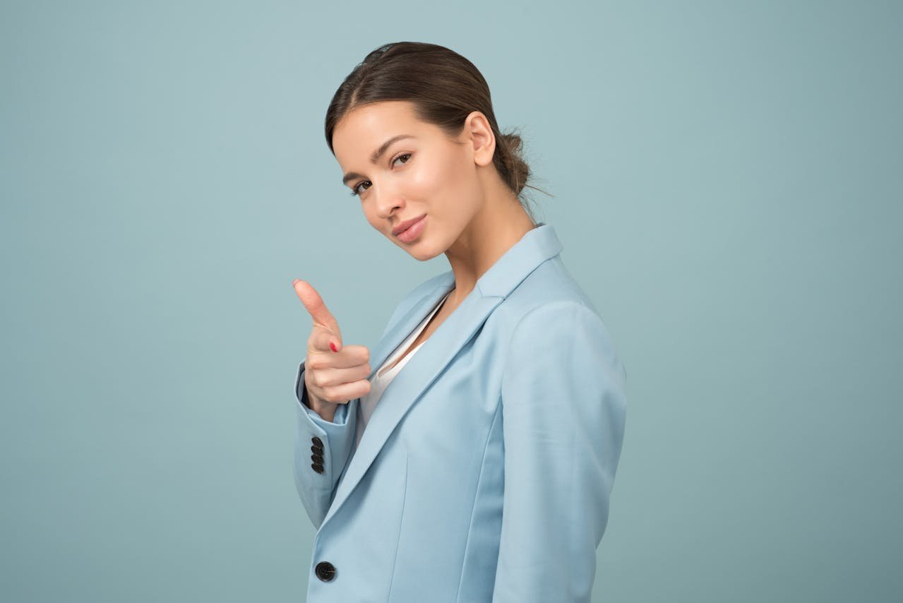 Confident woman entrepreneur in a blue suit pointing forward – representing empowerment, business growth, and grants for women entrepreneurs in 2025.