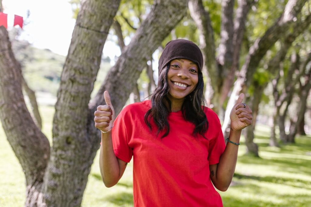 Smiling woman outdoors giving thumbs up, representing positivity and I Am Affirmations 2025