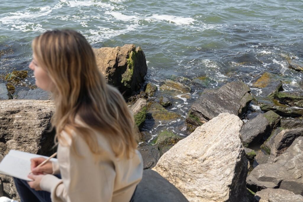  woman-sitting-on-rock-near-body-of-water-journaling-life changing habit
