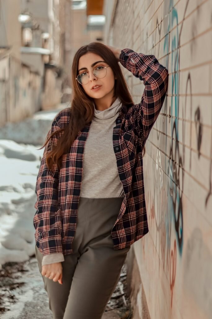 Woman wearing a brown plaid coat outdoors, casual city moment.