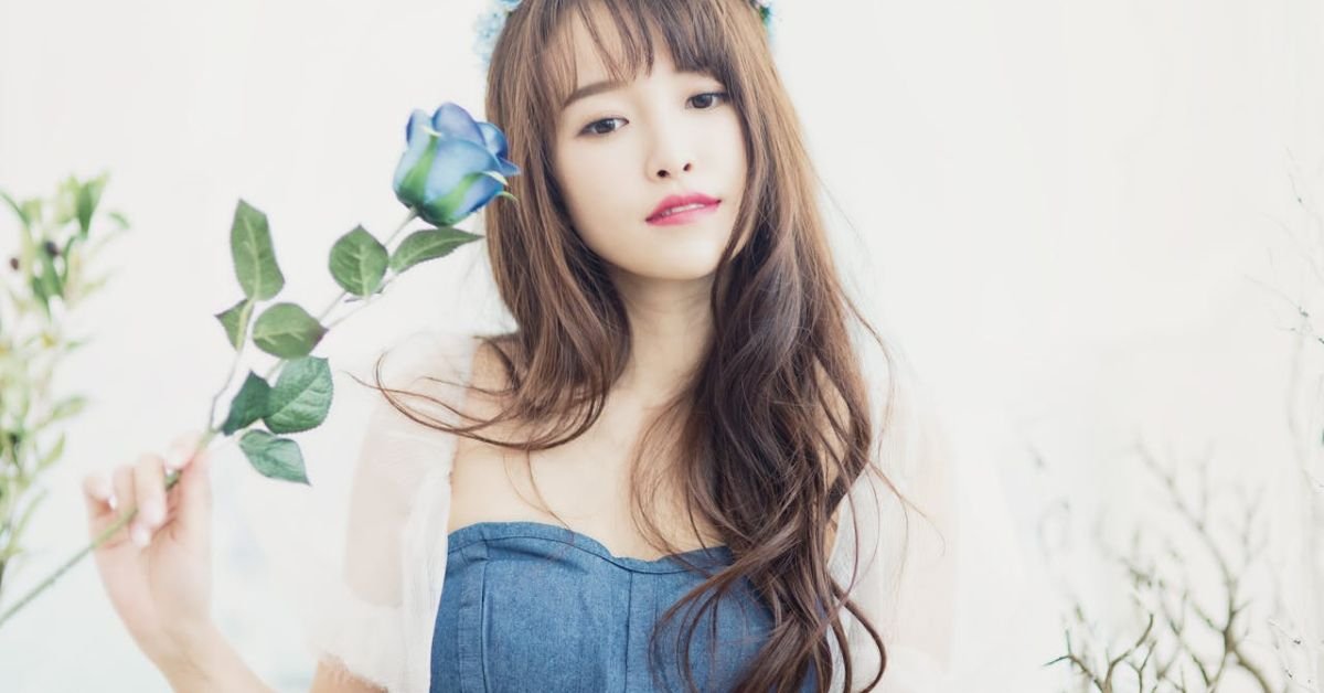 Young woman with radiant skin holding a flower, representing South Korean skincare and natural anti-aging beauty.