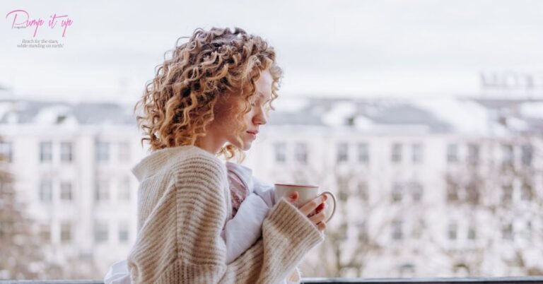 Woman wearing a chunky knit sweater holding a coffee mug on a winter morning.
