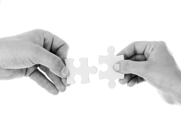 Two hands connecting puzzle pieces symbolizing learning, vocabulary growth, and problem-solving through word puzzle apps.
