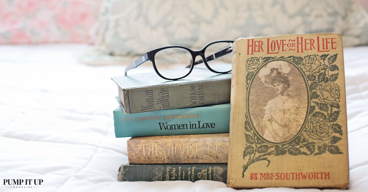 Stack of romance novels and reading glasses on a bed, representing the best enemies to lovers books