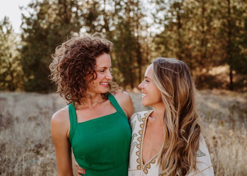 Two women sharing a joyful moment outdoors, representing connection, wellness, and women’s health.
