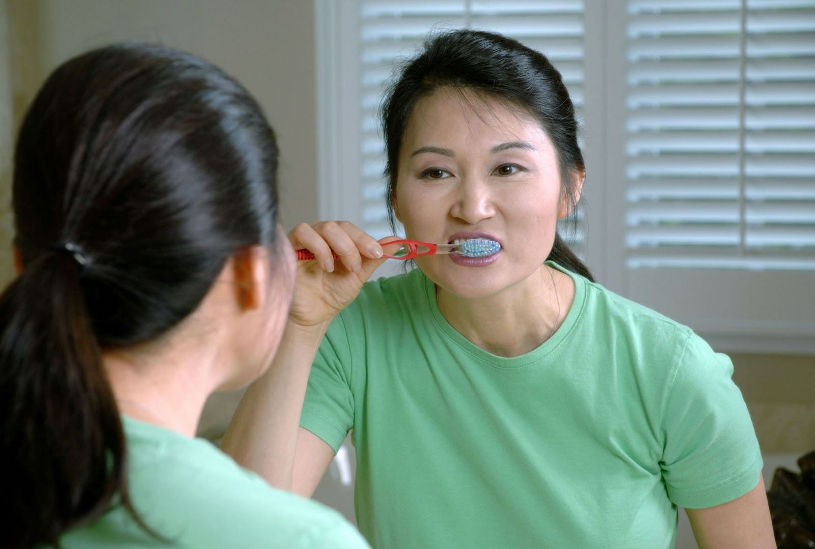 Person brushing teeth in mirror. showing gums