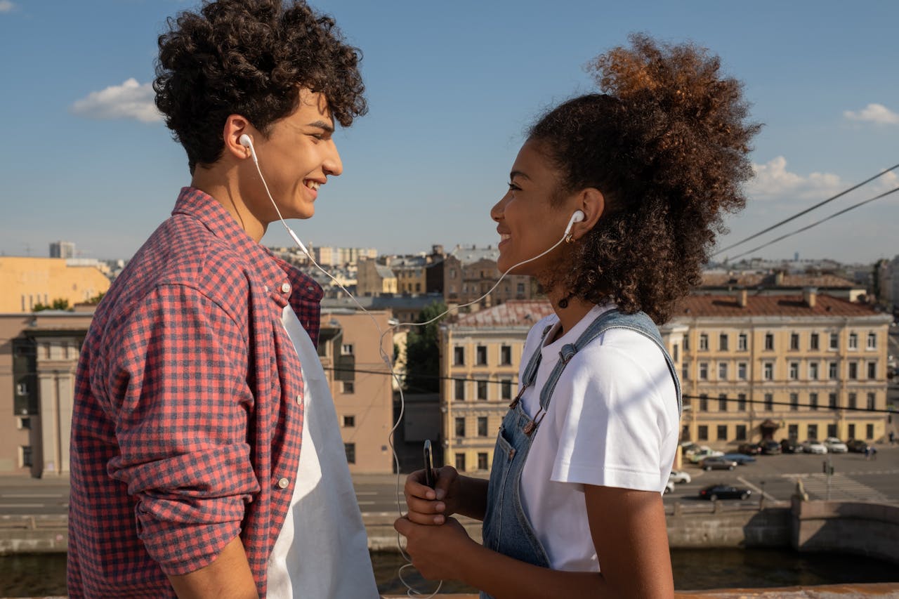 Young couple sharing earphones while listening to love songs, showing emotional connection through music