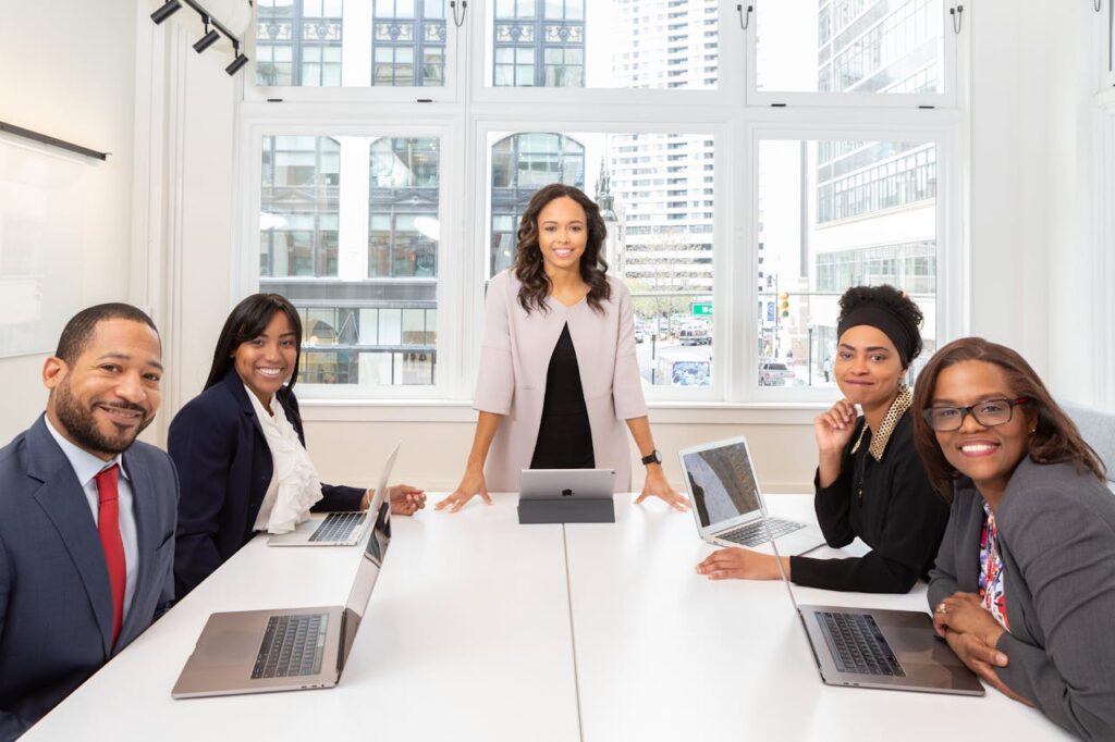 Entrepreneurs and professionals gathered around a table during a collaborative business meeting. Clear communication, confidence, and recognizing the value of your expertise are essential skills for women building successful businesses and strong professional networks.
