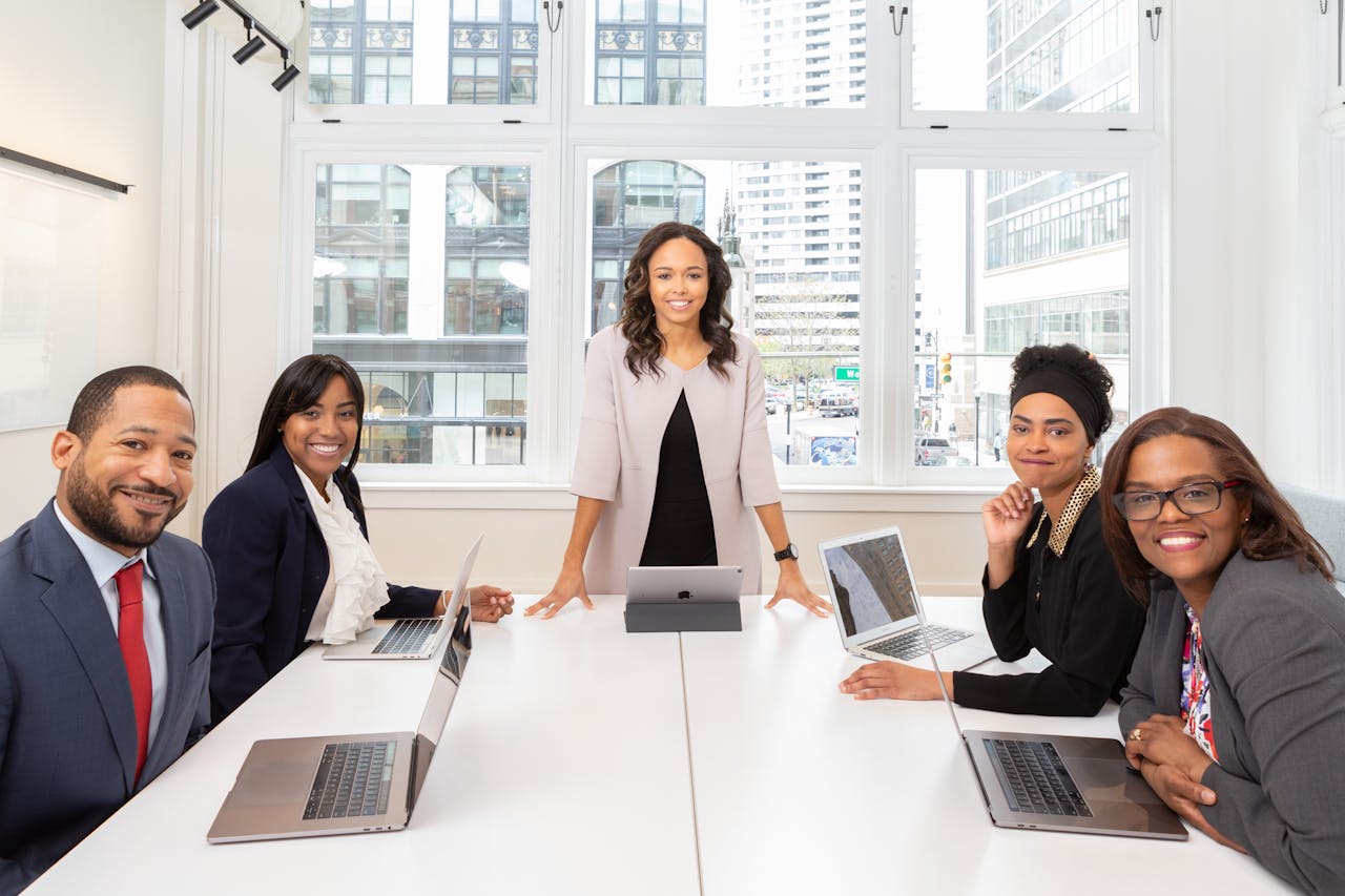 Entrepreneurs and professionals gathered around a table during a collaborative business meeting. Clear communication, confidence, and recognizing the value of your expertise are essential skills for women building successful businesses and strong professional networks.