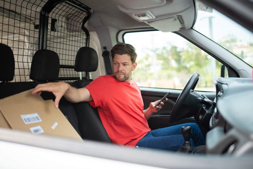 man-sitting-in-the-driver-sear-of-a-van-holding-a-cardboard-box-deliveries .jpg