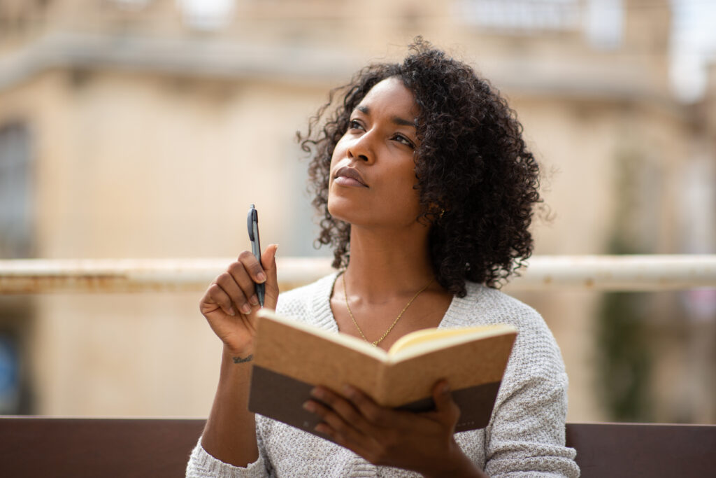 Portrait young african american woman thinking while writing in book confidence