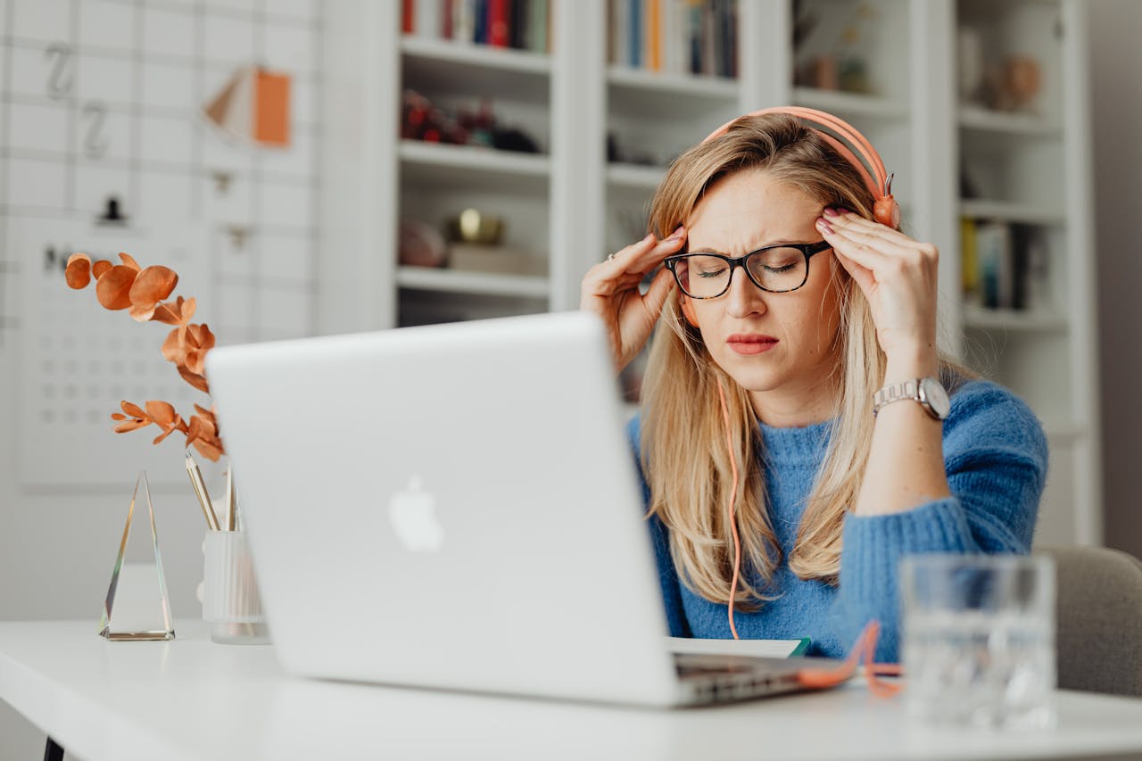 Stressed woman working on laptop representing burnout, anxiety, and habits that affect women’s confidence.