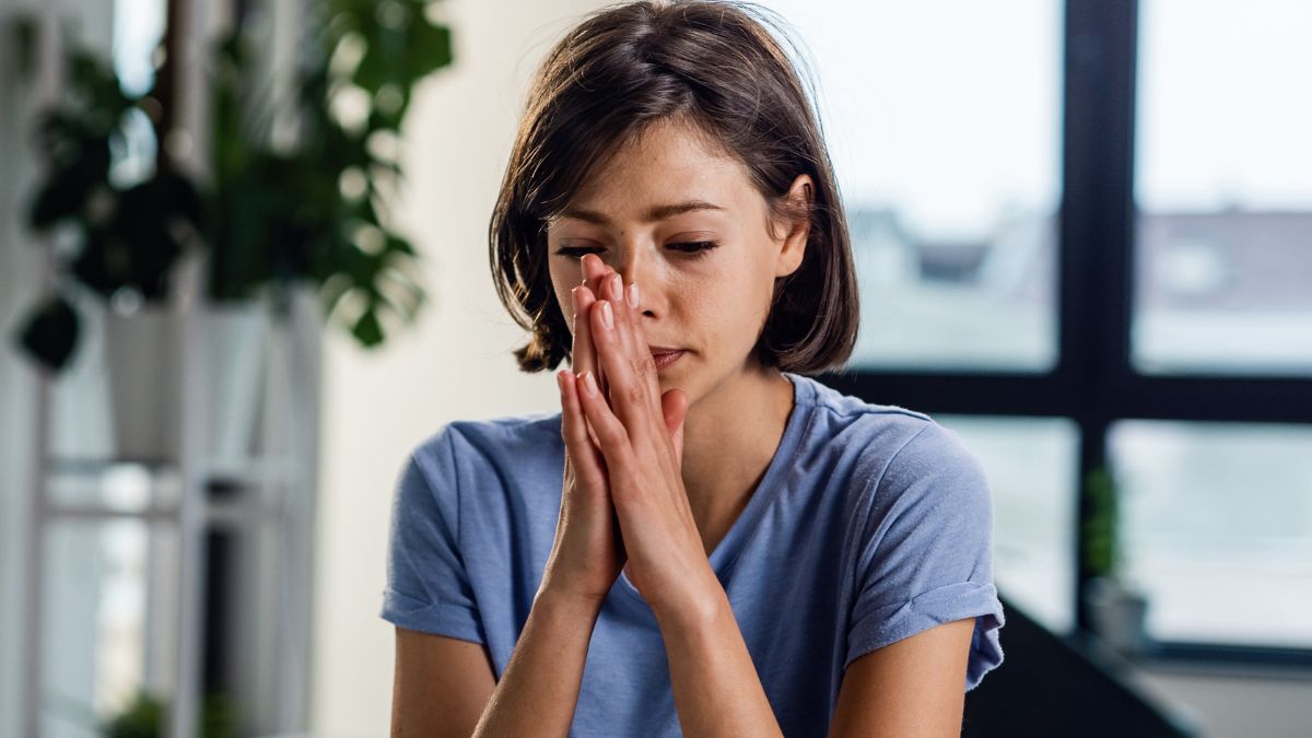 Woman sitting on bed overwhelmed with anxiety while dealing with stress and mental health struggles at home