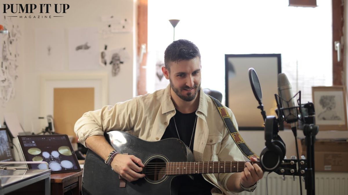 Independent musician recording acoustic guitar in a home music studio with microphone and recording equipment, representing indie artist development, music production, and music business growth.