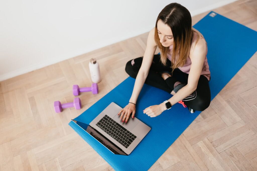 young-woman-with-laptop-sitting-on-yoga-mat-fitness website